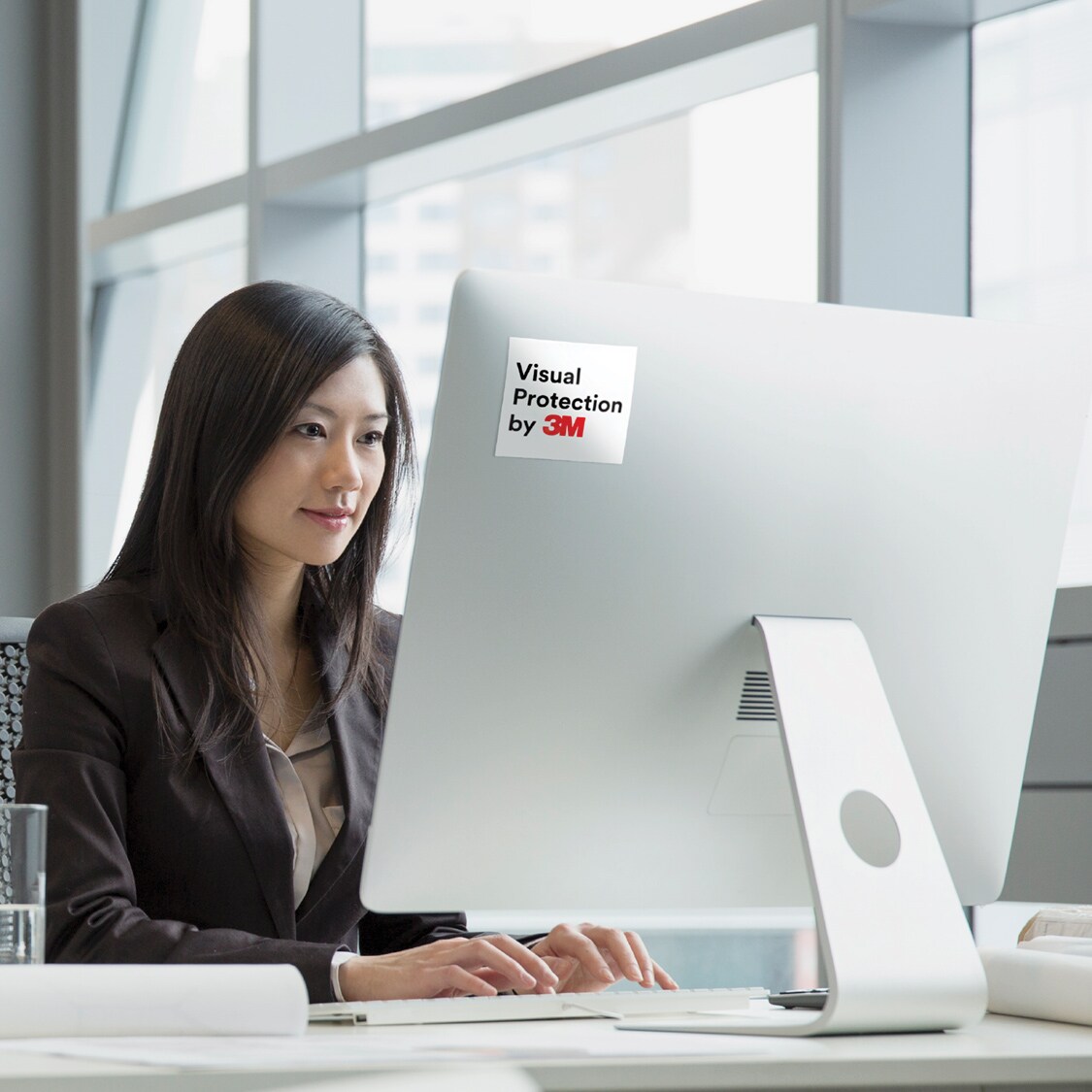 Woman working at computer protected by a 3M Privacy Filter.