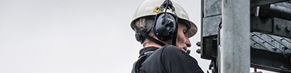 worker on metal structure wearing 3M safety headset
