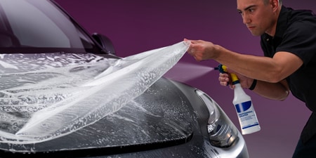 Installer applying 3M paint protection film to a car hood
