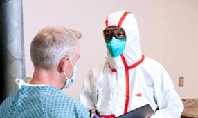 Clinician wearing PPE speaking with a patient
