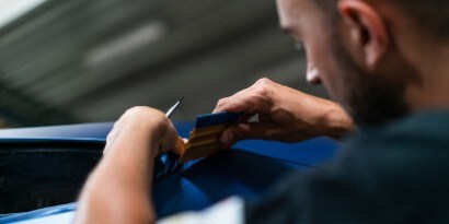 An installer uses a squeegee to install 3M™ Wrap Film on a vehicle.
