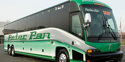 A big bus wrapped in a green and grey 3M graphic wrap with the words Peter Pan in green on the side of the bus.

