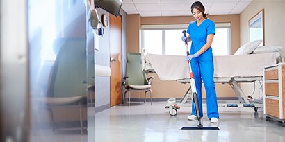 worker cleaning patient room floors
