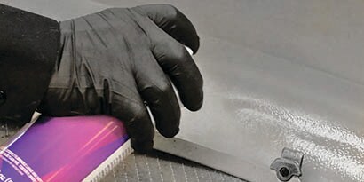 applying cavity wax to fender interior
