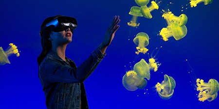 Woman exploring an underwater experience with an AR/VR headset.
