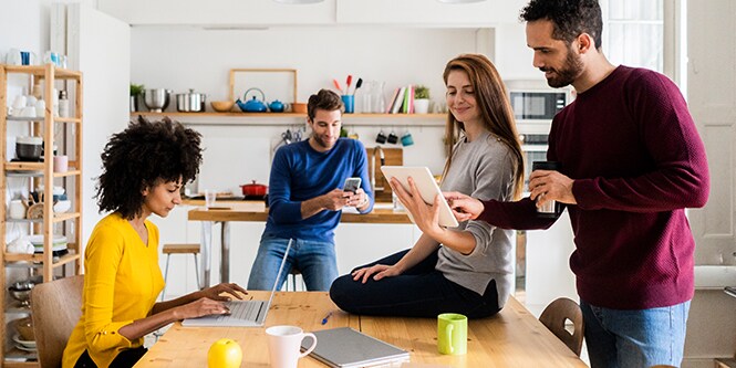 People in an office holding various consumer electronics including a laptop, a tablet, and a smartphone.
