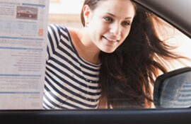 With anticipation, a young woman gazes past the window sticker to see the interior of a new car.