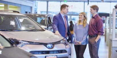 car sales associate and two customers in a dealership
