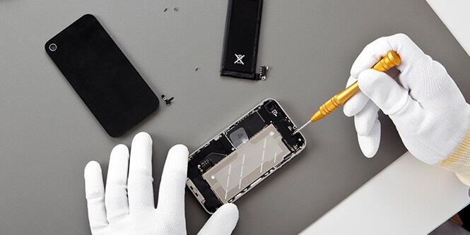Image of two hands investigating interior of a cell phone for electronics bonding.
