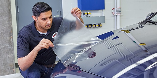 man applying clear bra to a vehicle