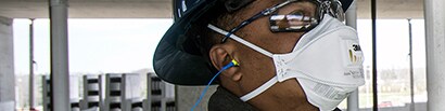 construction worker wearing earplugs and disposable respirator
