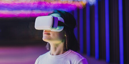 A woman looking up and to their right with a slim white VR headset.
