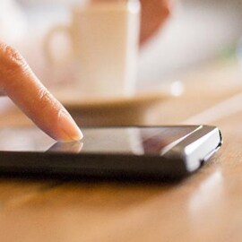Person touching a smartphone screen that used 3M's electronics enclosure bonding solutions.