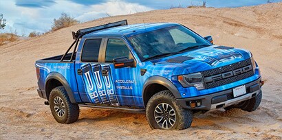 A big Ford truck wrapped in a blue and black 3M IK180mC-10 graphic wrap, driving in the desert.