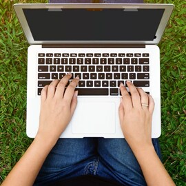 Person on laptop outside sitting on grass
