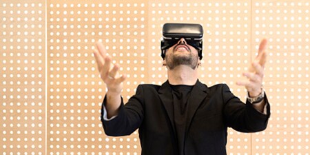 A man fully immersed in his VR headset on a modern light grid backdrop.
