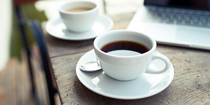 Coffee and hot tea in cups on top of plate saucers
